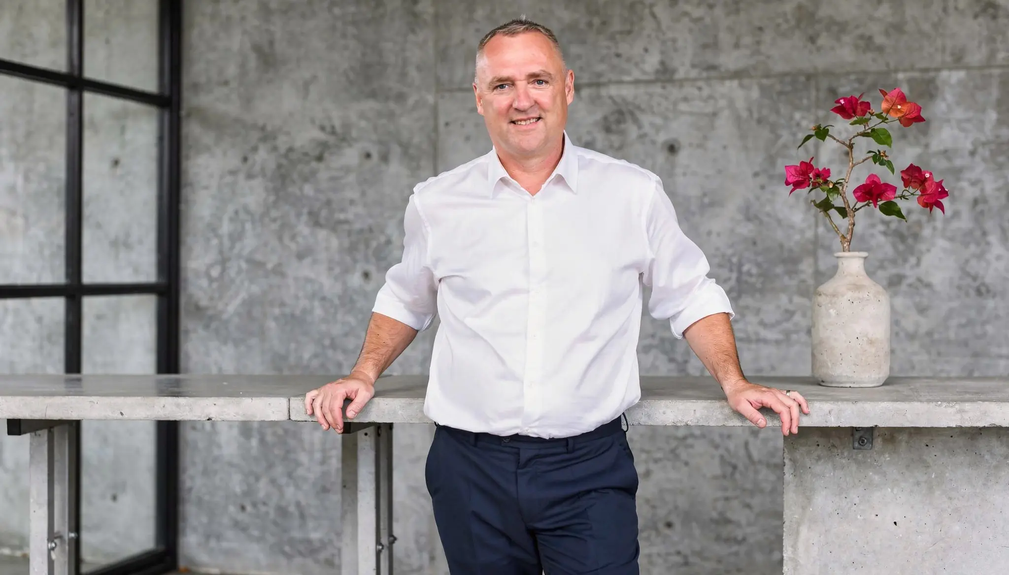 Kühle Betonfläche mit einem einzelnen rosafarbenen Farbakzent in reduzierter, industrieller Bildsprache.